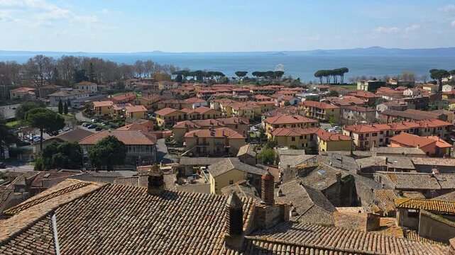 Panoramic view of Bolsena medieval town with red clay tile roofs and Lake Bolsena in the background, Lazio, Italy