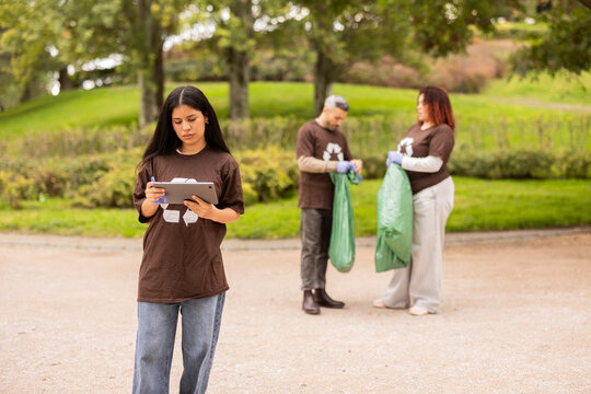 Volunteers cleaning park and recording data on tablet