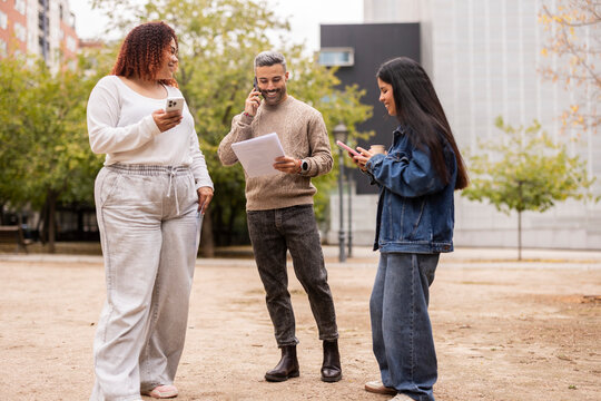 Multiethnic friends using smartphones and documents