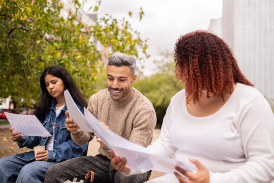 Multiethnic friends reviewing documents outdoors
