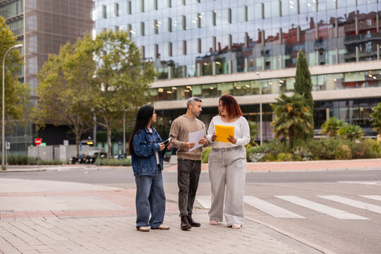 Multiethnic friends sharing documents outdoors