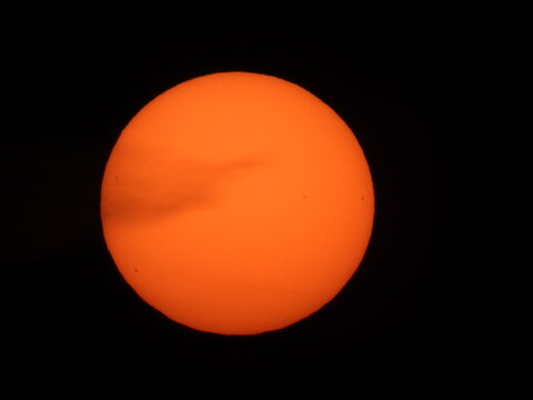 Dramatic close-up of a massive orange sun rising on the horizon, captured with a super telephoto lens