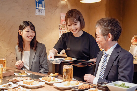 居酒屋で料理を提供する女性スタッフ