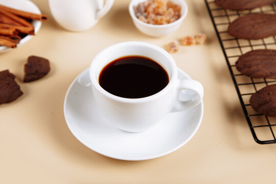 Coffee with madeleines and cinnamon sticks on table