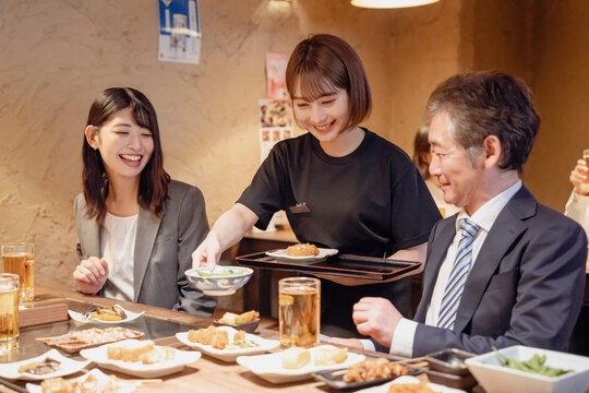 居酒屋で料理を提供する女性スタッフ