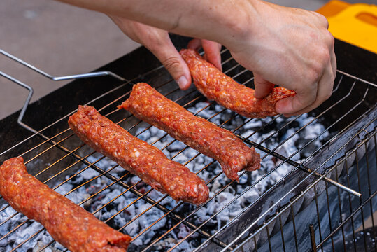 Grilling raw kofta kebabs on an outdoor barbecue