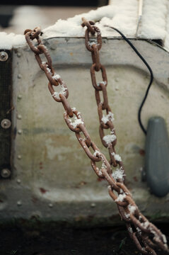 Snow-covered rusty chain on an industrial surface