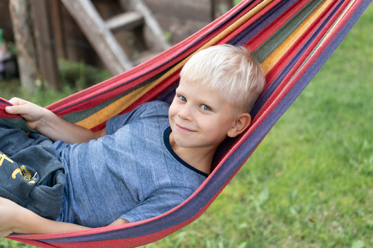 Boy relaxing in colorful hammock outside on a sunny day