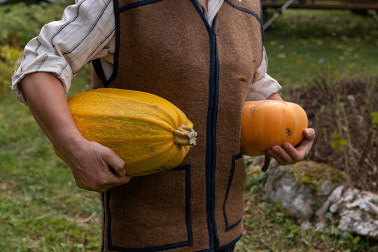 Farmer holding large yellow squash and orange pumpkin