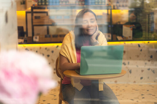 Woman working on laptop by the window in a cafe