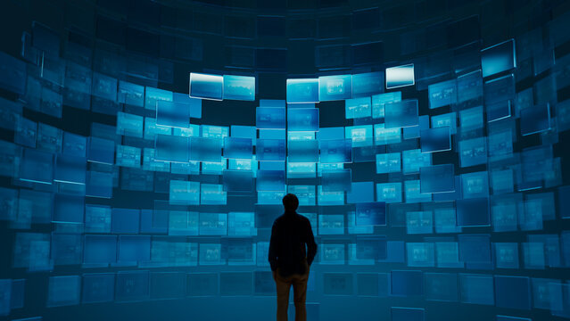 Silhouette of man observing multiple digital screens with graphics