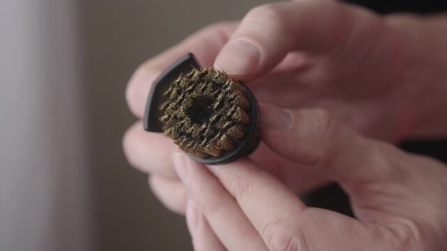 Close-up hands of person holding and examining new steam cleaner nozzle with brass brush, preparing for effective sanitization and cleaning of various surfaces, emphasizing thoroughness and readiness.