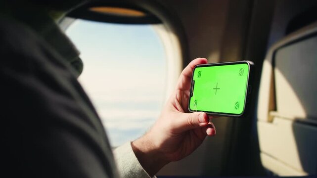 Man tourist using smartphone with green screen while traveling by train or bus, travelling application, male working during business travel. 