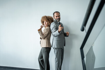 Fototapeta premium Business colleagues standing back to back pointing to camera