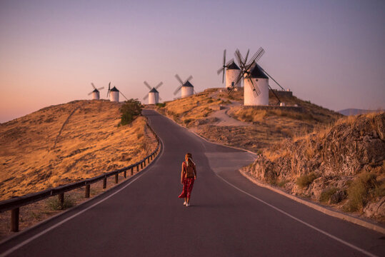 Woman exploring Consuegra's windmills at sunset