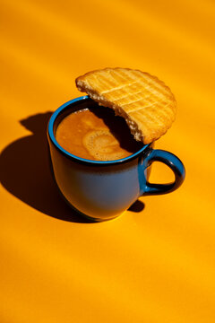Coffee mug with cookie on bright orange backdrop