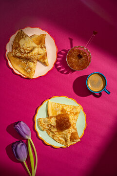 Delicious crepes with jam and coffee on vibrant table