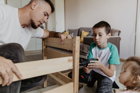 Father and son assembling a wooden baby cot together