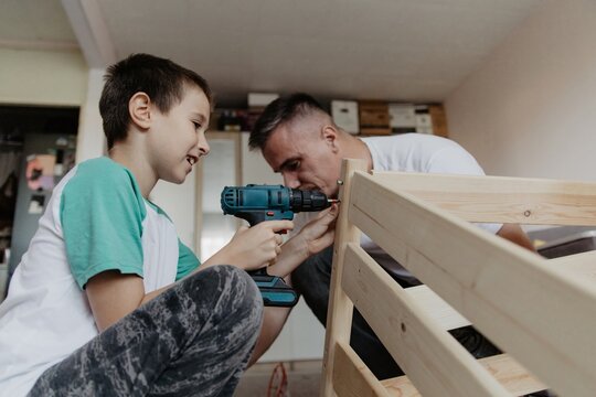 Father guides son in assembling a wooden baby cot