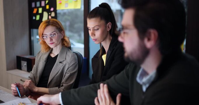 Group works on project in office during afternoon, discussing ideas and brainstorming solutions for business challenges