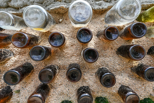 View of embedded glass bottles creating a quirky, textured wall, contrasting clear and amber against the rough, sandy mortar, Santa Fe, New Mexico, United States.