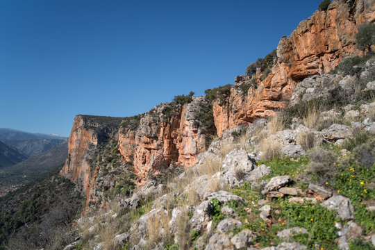 View of iconic red cliffs above Leonidio in Greece captured on a clear sunny day.