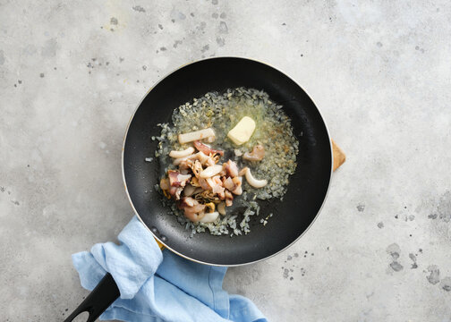 Cooking seafood and onions in a pan with butter on a kitchen counter in the afternoon