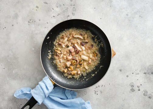 Cooking seafood and vegetables in a frying pan on a kitchen countertop during daytime