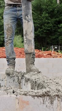Worker uses concrete pump to pour to blocks foundation at construction site