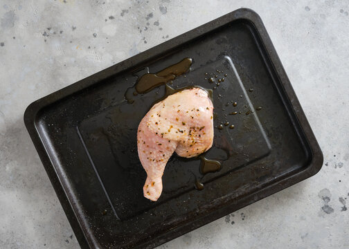 Chicken leg piece placed on a baking tray ready for cooking in a kitchen setting