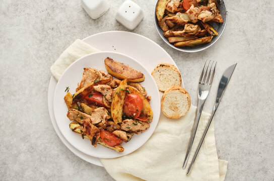 Delicious dish with chicken, vegetables, and bread served on a white plate and a small bowl nearby
