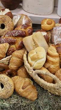 Baskets overflowing with different kinds of bread variety of shapes in local bakery setting.