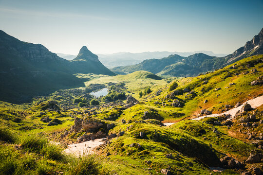 Rolling green hills and majestic cliffs under a clear blue sky at dawn. Location place Durmitor National park, Stozina peak, Montenegro, Europe.