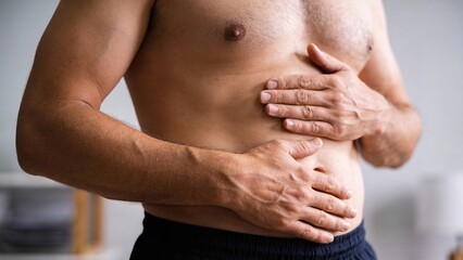 Naklejka premium Shirtless Man Clutching Stomach And Chest, Bright Home Interior, Closeup Torso And Hands Pressing Abdomen, Subtle Natural Light Highlighting Skin