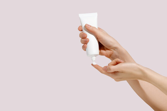 Woman Squeezing Cosmetic Cream from Tube into Hand. Cosmetic beauty product branding mockup. Copy space