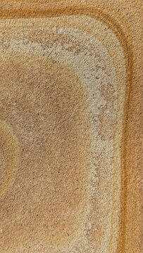 Natural sandstone texture with orange and brown Liesegang rings, rhythmic mineral bands on stone surface