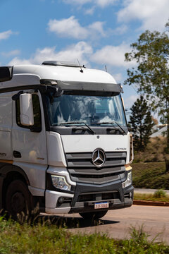 White Mercedes-Benz Actros front half close up in movement, Heavy duty truck driving on highway 