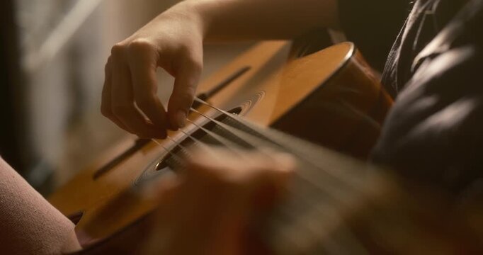retro cinematic close-top view  of teenage hands playing a classical guitar in warm sunset light. Fingers gently move across the strings