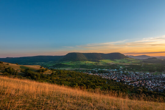 Panoramic Sunset Over a Rural Village Nestled in a Lush Green Valley with Rolling Hills in the swabian alb
