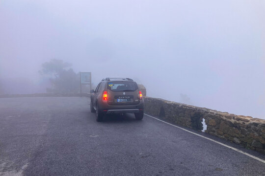 Renault Duster on foggy hiking trail leading toward Sierra Bermeja and the Reales peaks with misty mountain atmosphere near Estepona, Spain.