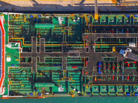 Aerial view of a vibrant, intricate ship with complex piping and machinery, a geometric tapestry of industrial prowess against the blue sea, Ortona, Abruzzo, Italy.