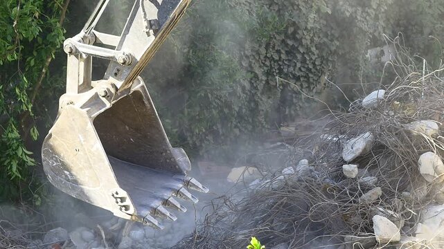 Excavator works to get rid of building demolition rubbish. Concrete dust released, a major source of dangerous air pollution. Construction contains lead, asbestos or other hazardous substances 