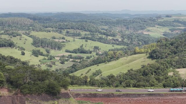 Ve�culos em uma rodovia com belos campos verdes e bosques. BR 282.