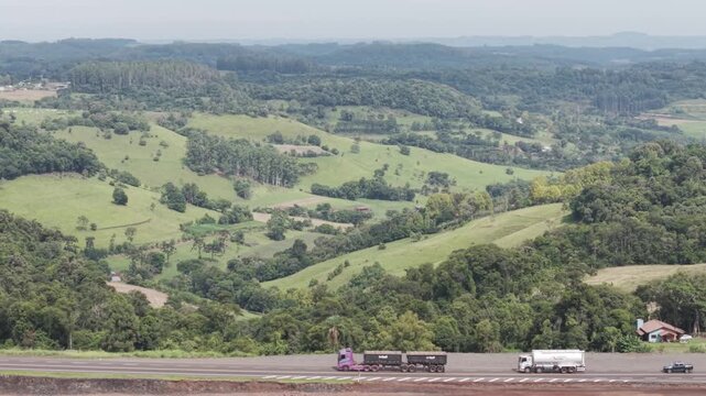 Ve�culos em uma rodovia com belos campos verdes e bosques. BR 282.