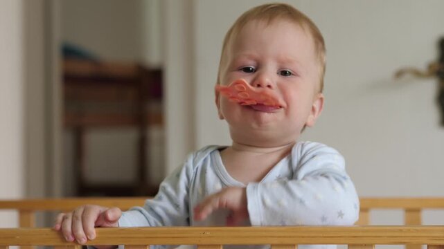 Joyful teething moment. Adorable infant enjoying first teething experiences in cozy nursery setting. Cute baby chewing teether with messy lips while exploring textures in peaceful morning environment