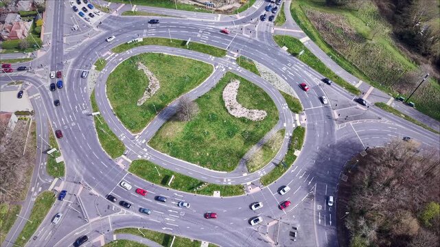 Drone aerial view of a large multi-lane roundabout with flowing traffic and road markings in Basingstoke, United Kingdom. Urban transport infrastructure with cars navigating junction and green central