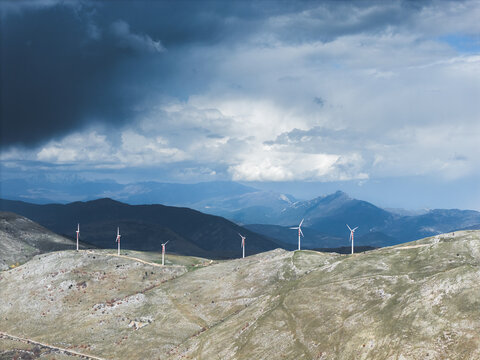 Aerial view of wind turbines standing tall against the backdrop of rolling hills and a dramatic sky, Cocullo, Abruzzo, Italy.