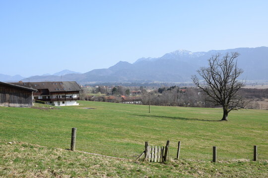 Spring countryside near Murnau am Staffelsee with traditional farmhouses, green meadows, and the Bavarian Alps in the background.