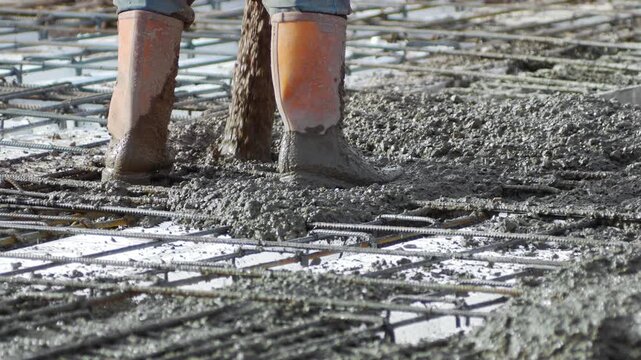 A skilled construction worker  delivery of concrete mix. A laborer expertly maneuvers a large hose connected to a concrete pump to accurately fill the reinforcing steel cages at the construction site