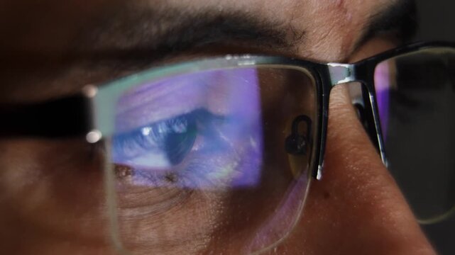Man's eye reflecting a computer screen at night